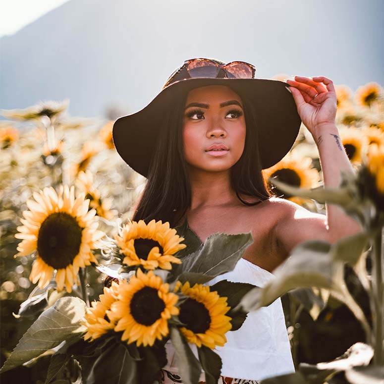 young woman standing in a field of sunflowers on a sunny day