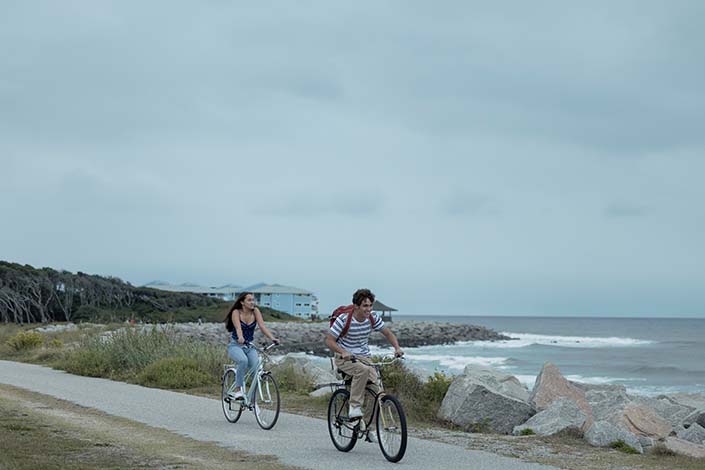 two people riding bikes on the beach