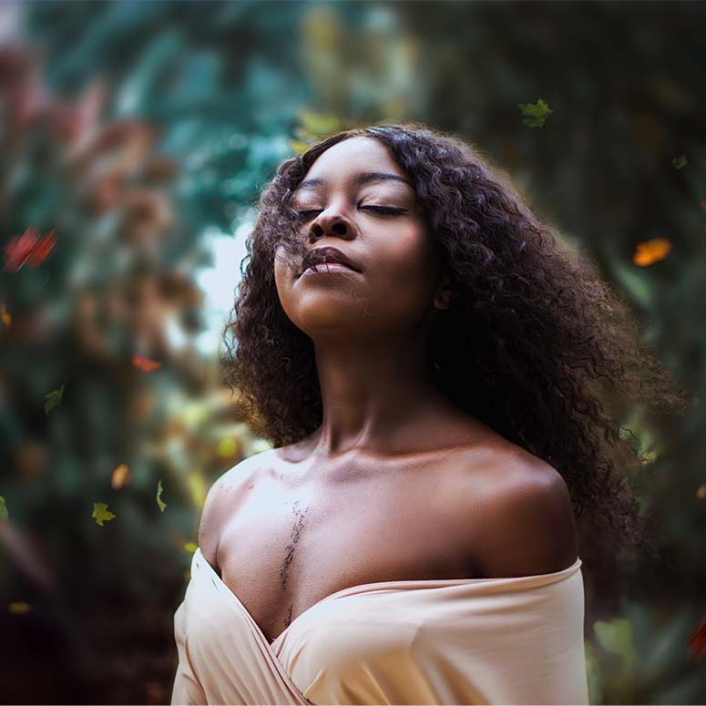A young Black woman stands with her eyes closed amid a green, garden-like background
