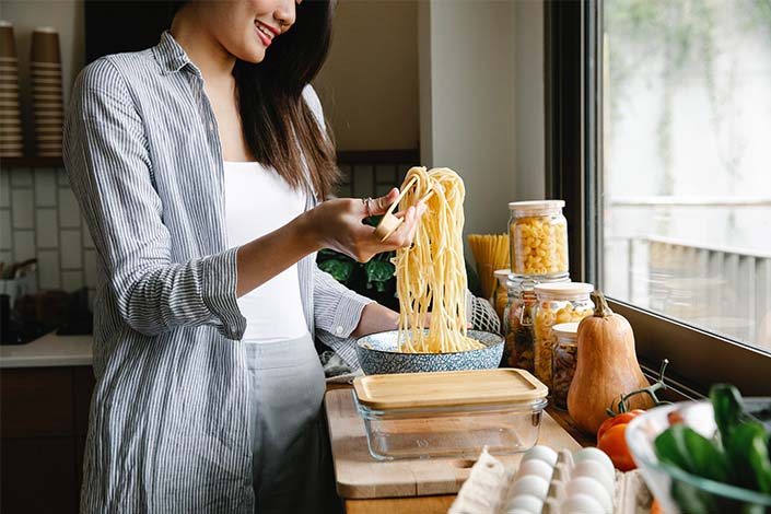 A young woman makes a big batch of pasta in the kitchen