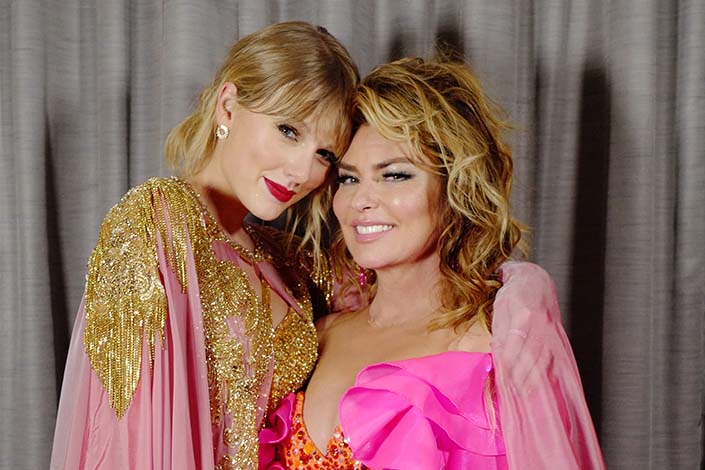 Taylor Swift and Shania Twain, both wearing pink-and-gold outfits