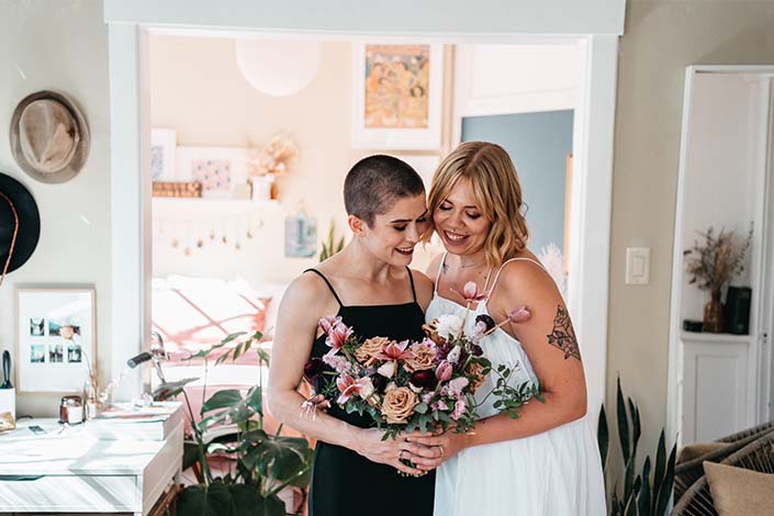 Two smiling people holding a bouquet of flowers together