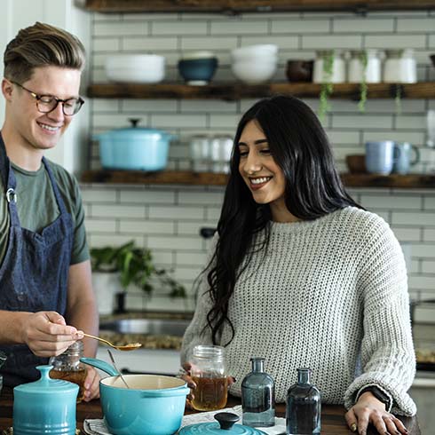 A smiling young man and woman cook together