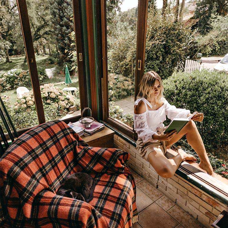 A woman sits on a windowsill reading