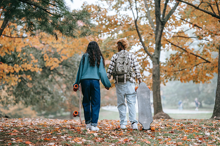 A couple holding hands and walking in the fall forest