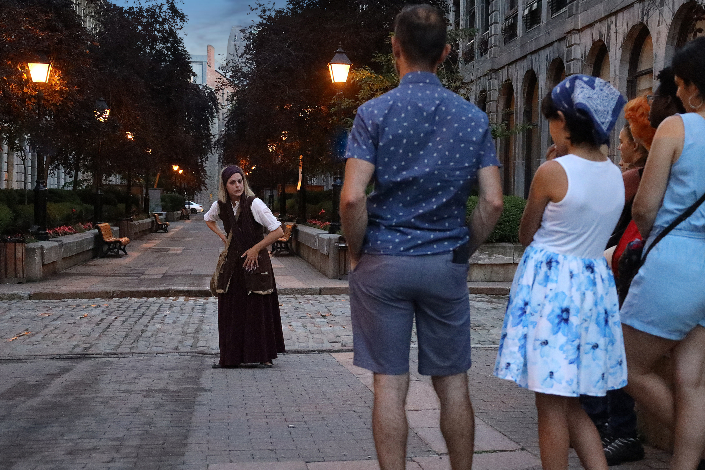 An actor in costume leading a ghost tour through Old Montreal