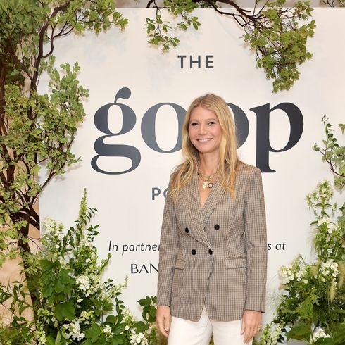 Gwyneth Paltrow poses in a blazer and dress pants at a Goop event.
