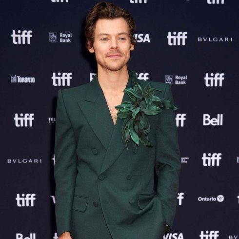 Harry Styles poses in a dark green suit at TIFF.