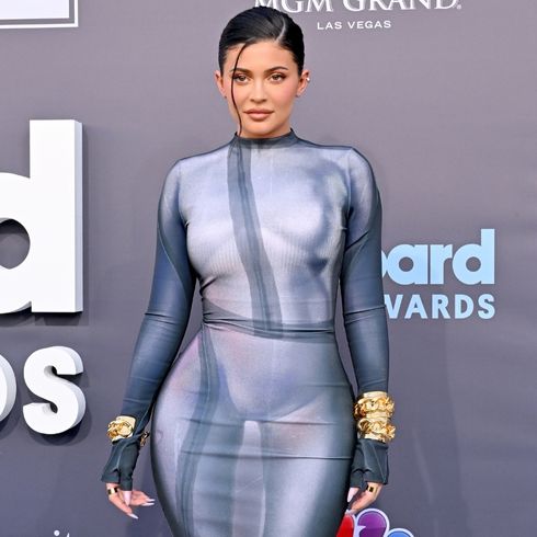 Kylie Jenner attends the Billboard Awards in a long sleeve, fitted blue and grey dress with her hair pulled back.