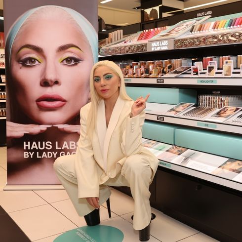 Lady Gaga poses in cream blazer while crouching in front of Haus Labs at Sephora.