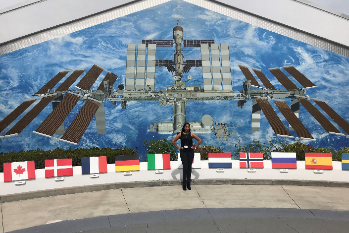 A woman standing in front of an image of the International Space Station at NASA in Florida