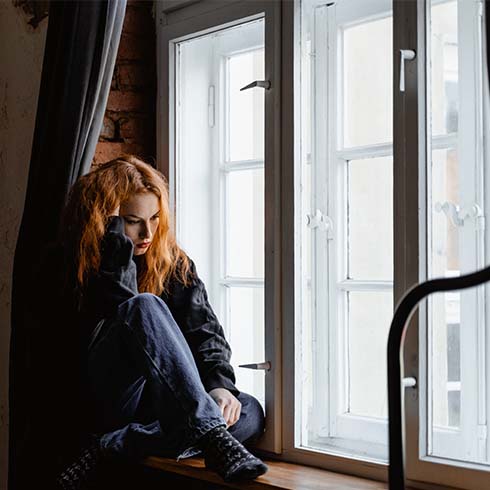 A sad woman sitting near a window