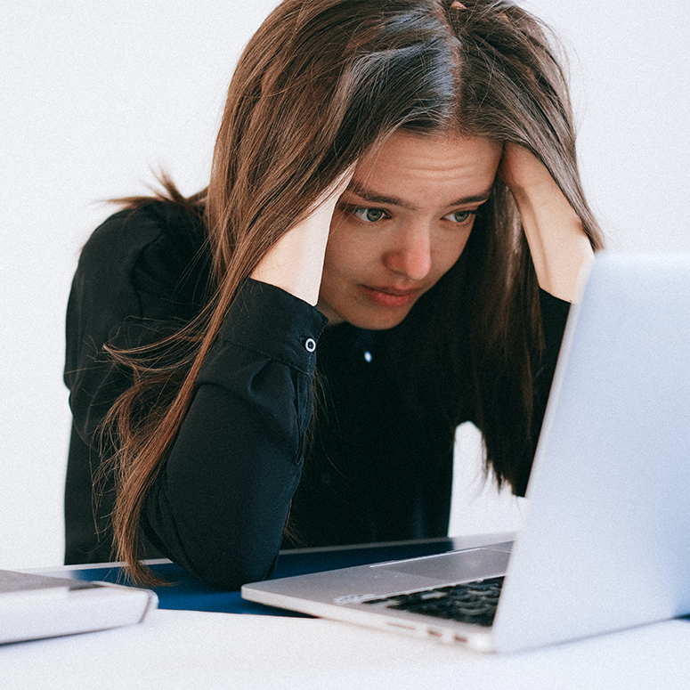 A woman looking stressed at a laptop computer