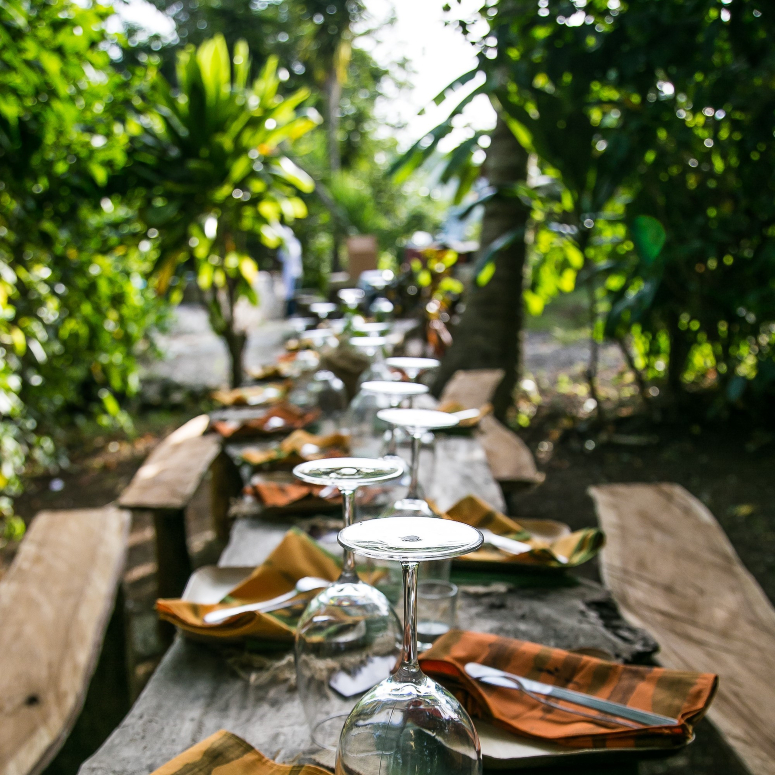 An al fresco dining table and seating set among palm trees in Jamaica