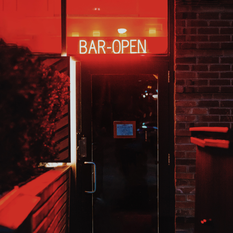 An entrance to a bar with a red neon sign