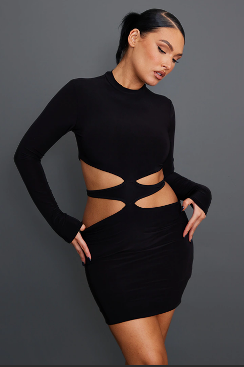 A woman poses while wearing a black bodycon dress featuring cutouts at the waist