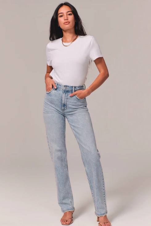 A woman wears a white T-shirt and faded blue straight-leg jeans