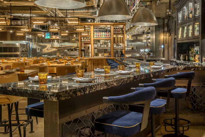 The interior of Taverna Mercatto in Toronto with communal marble topped bar and blue velvet seating
