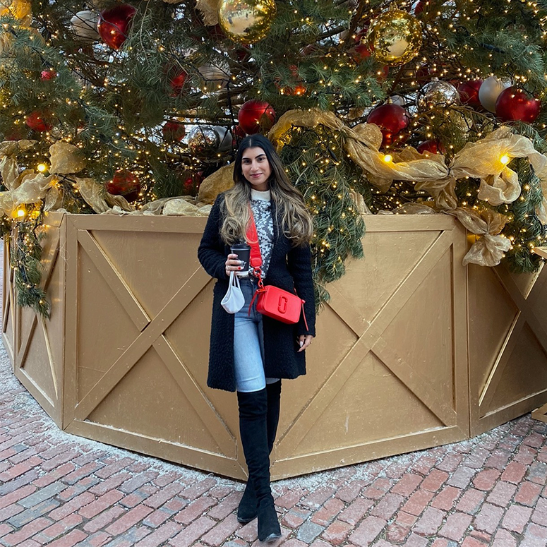 A young woman stands in front of a big Christmas tree