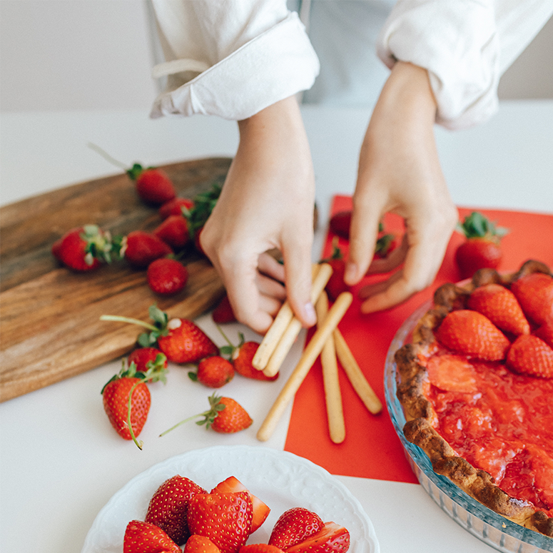 Two hands preparing strawberries