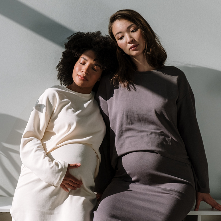 Two pregnant women sit side-by-side.