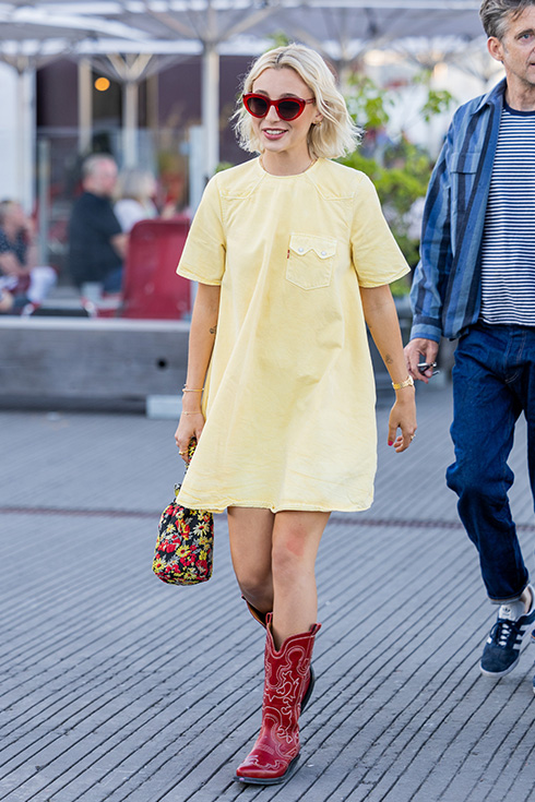 Emma Chamberlain wearing a yellow dress and red cowboy boots