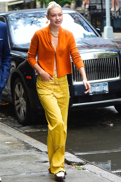Gigi Hadid wearing yellow pants and an orange cardigan