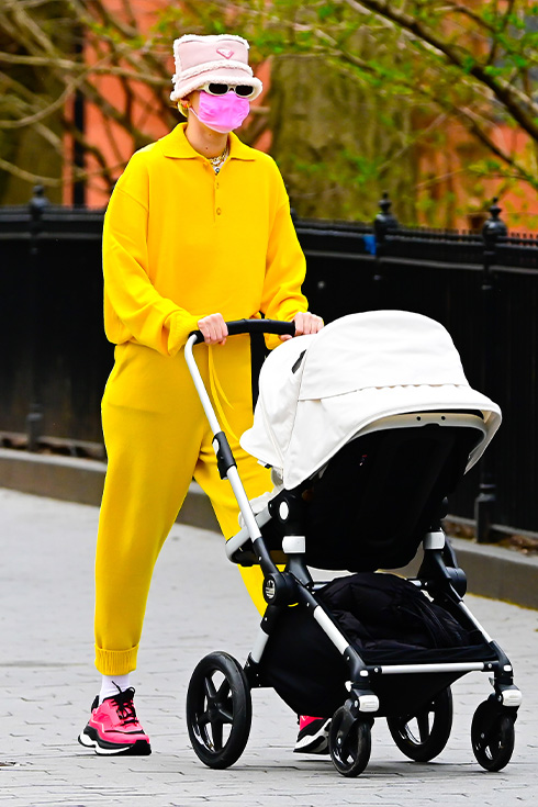 Gigi Hadid wearing a yellow lounge set pushing a stroller