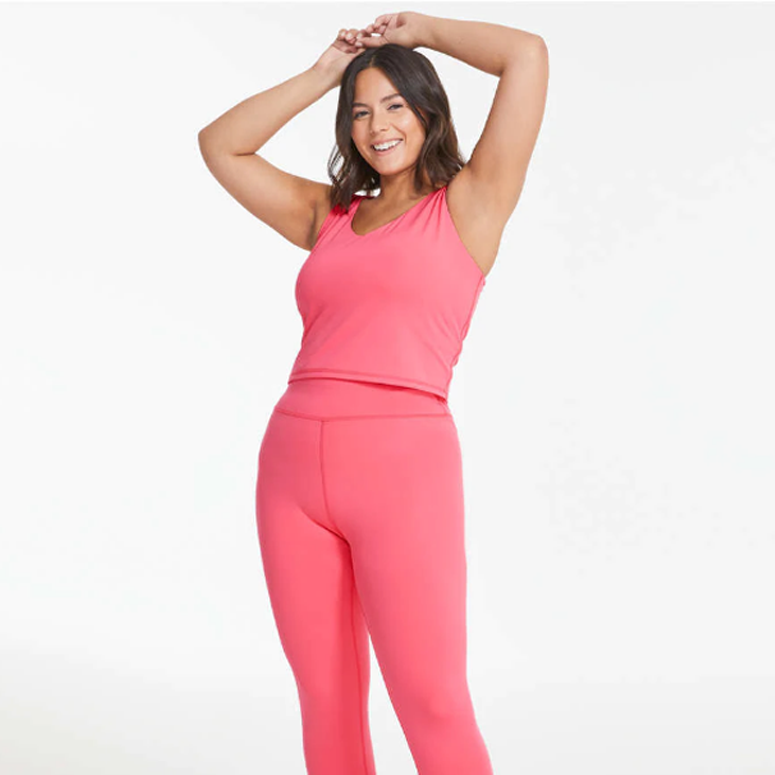 A woman wearing a pink V-neck top and leggings.