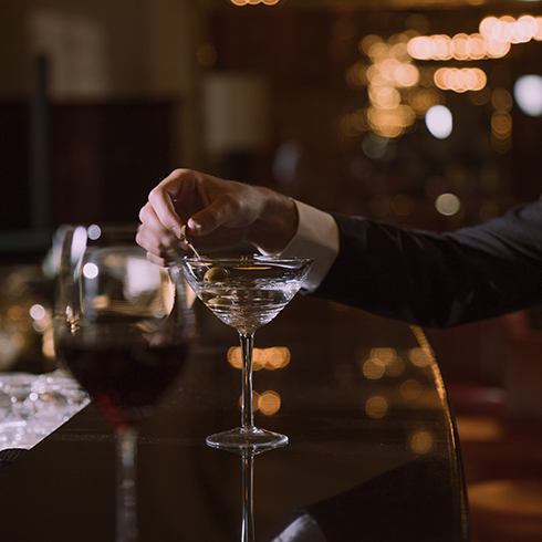 A man's hand holding a martini at a bar