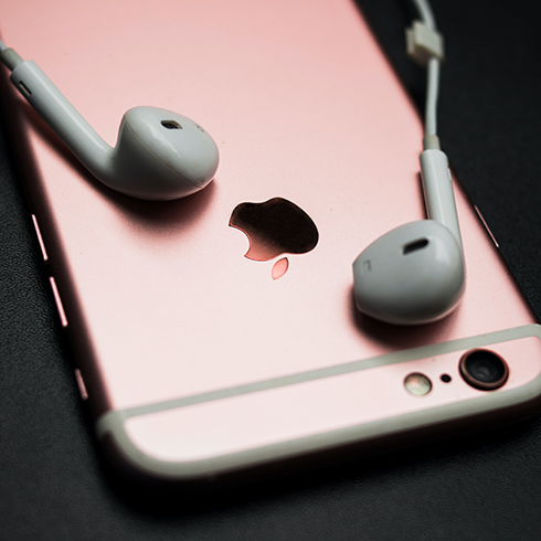 A rose gold iPhone with headphones plugged in