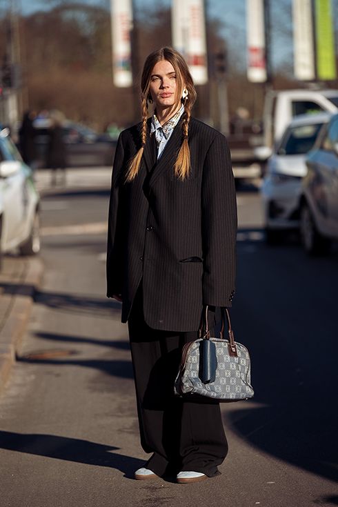 Lois Schindeler wearing a black oversized suit, light blue shirt with pattern and two braids hair style outside Helmstedt during the Copenhagen Fashion Week Autumn/Winter 2023 on February 02, 2023 in Copenhagen, Denmark. 