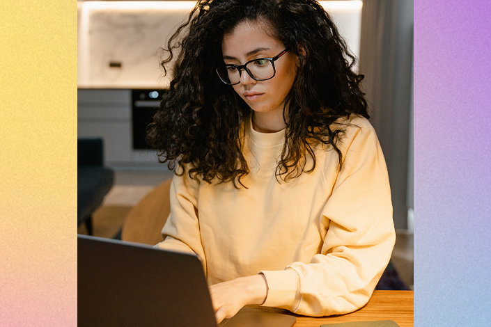 A woman in a yellow sweater looking at her laptop