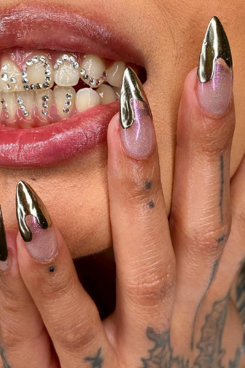 A shot of a woman with long chrome-tipped nails and tooth gems