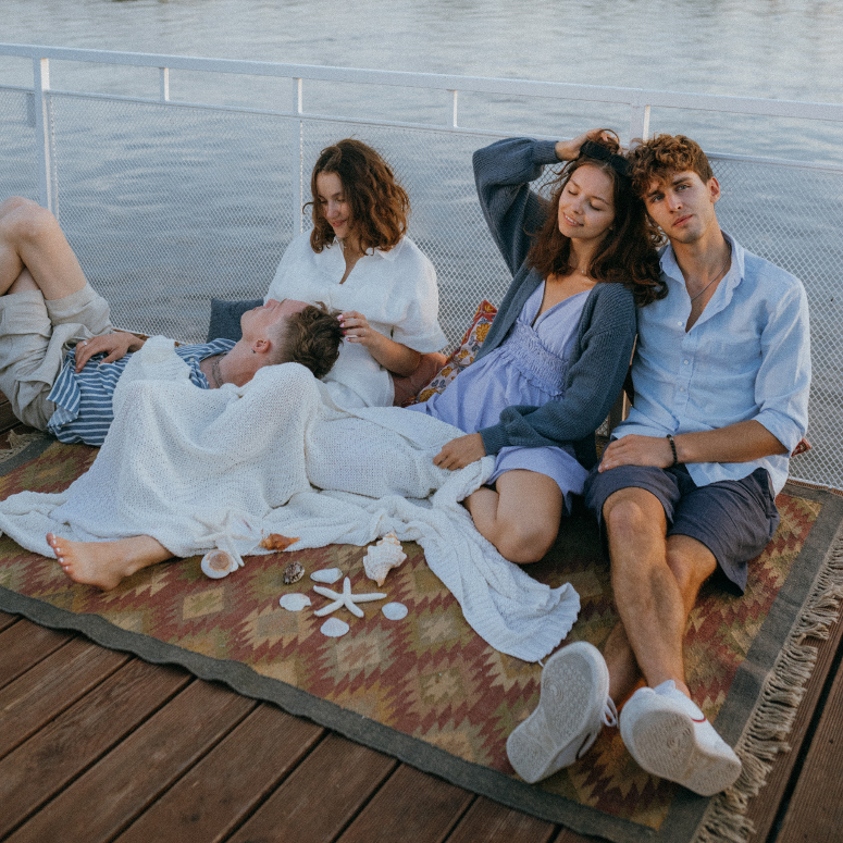 A shot of four young people on a double date sitting on a dock by the water