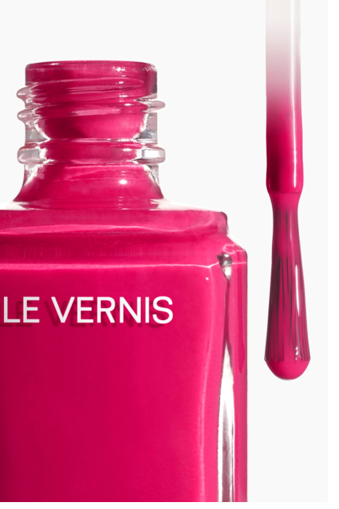 A closeup of a bottle of Chanel Le Vernis nail polish in a magenta pink