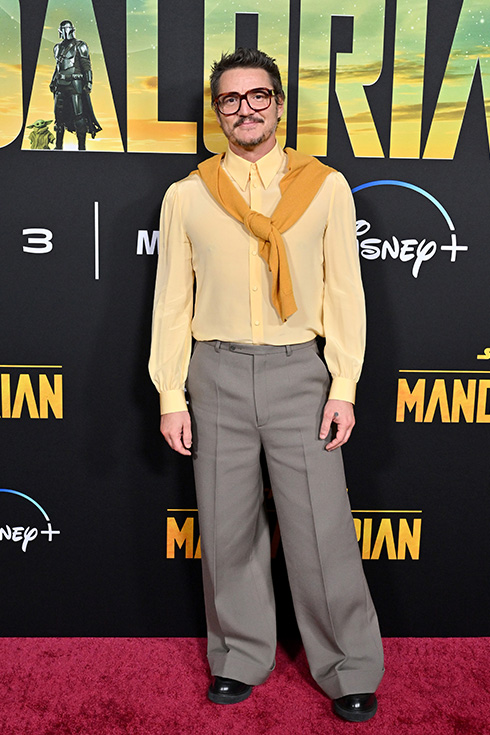 Pedro Pascal on the red carpet in a yellow cardigan and matching scarf