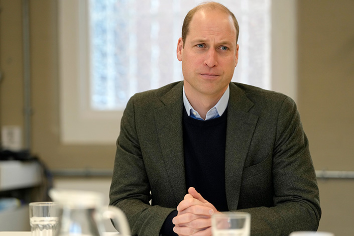 Prince William seated at a desk, with a stern look