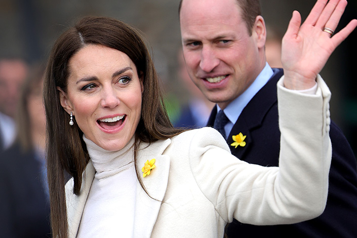 Kate Middleton waves to a crowd, with Prince William in the background