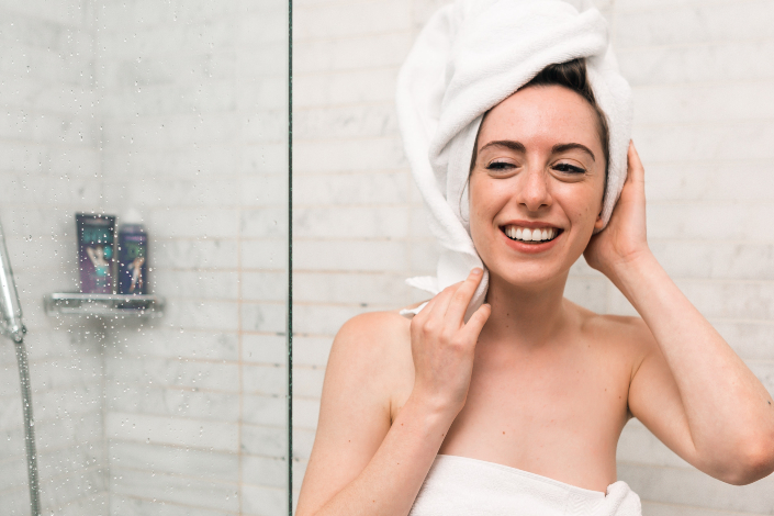 A woman getting out of the shower with a towel on her head