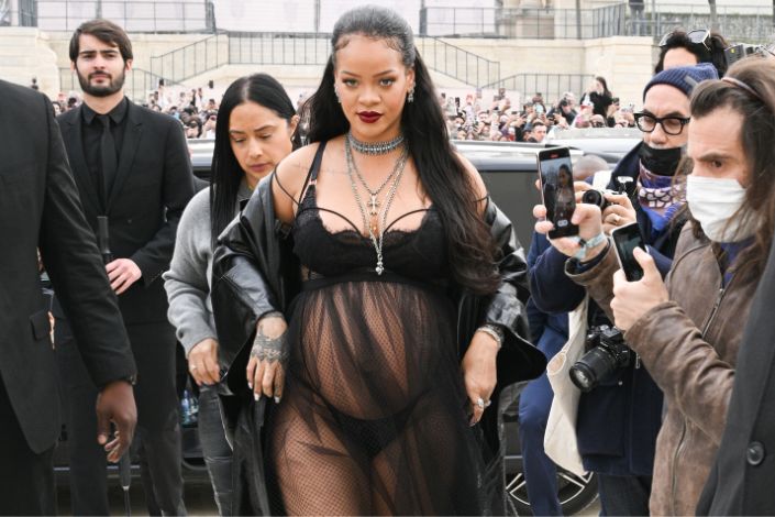 Rihanna in a sheer black dress, pregnant, surrounded by paparazzi 