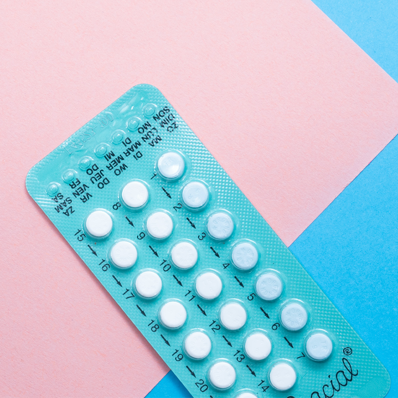 A package of birth control in front of a pink and blue background