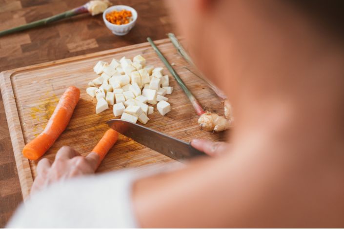 A photo of a person chopping vegetables on a cutting board.