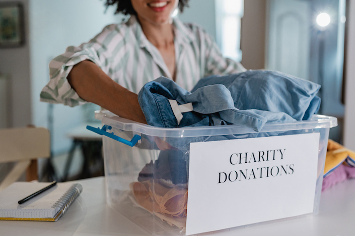 Person organizes clothing for donation into a clear and labelled box