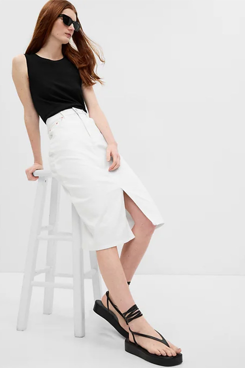 Woman sitting on a stool wearing a white slit skirt