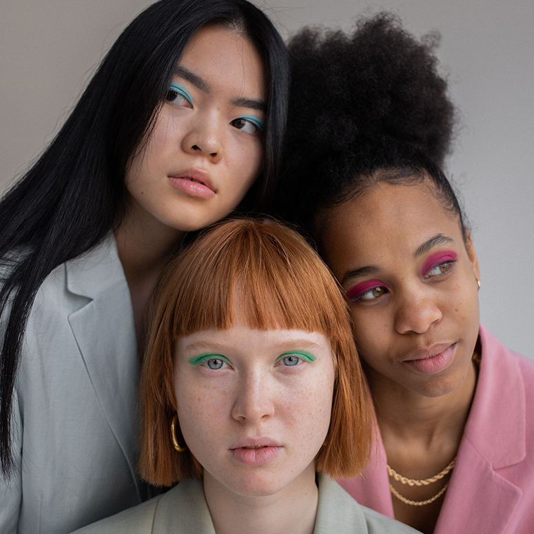 Three women with different hairstyles, colourful suits and makeup